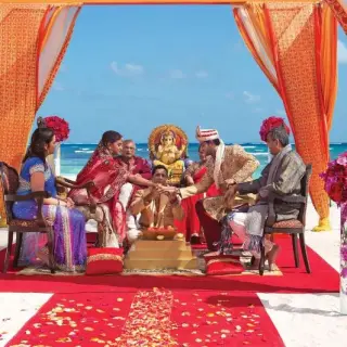 South Asian wedding ceremony under an orange mandap on the beach at Dreams Cap Cana, Punta Cana