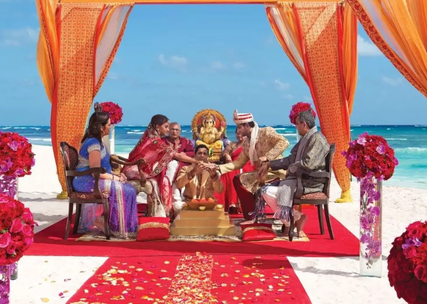 South Asian wedding ceremony under an orange mandap on the beach at Dreams Cap Cana, Punta Cana