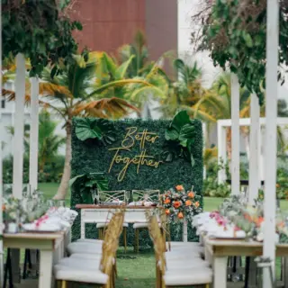 Garden wedding reception at Dreams Cap Cana, Punta Cana featuring long wooden tables and a greenery backdrop