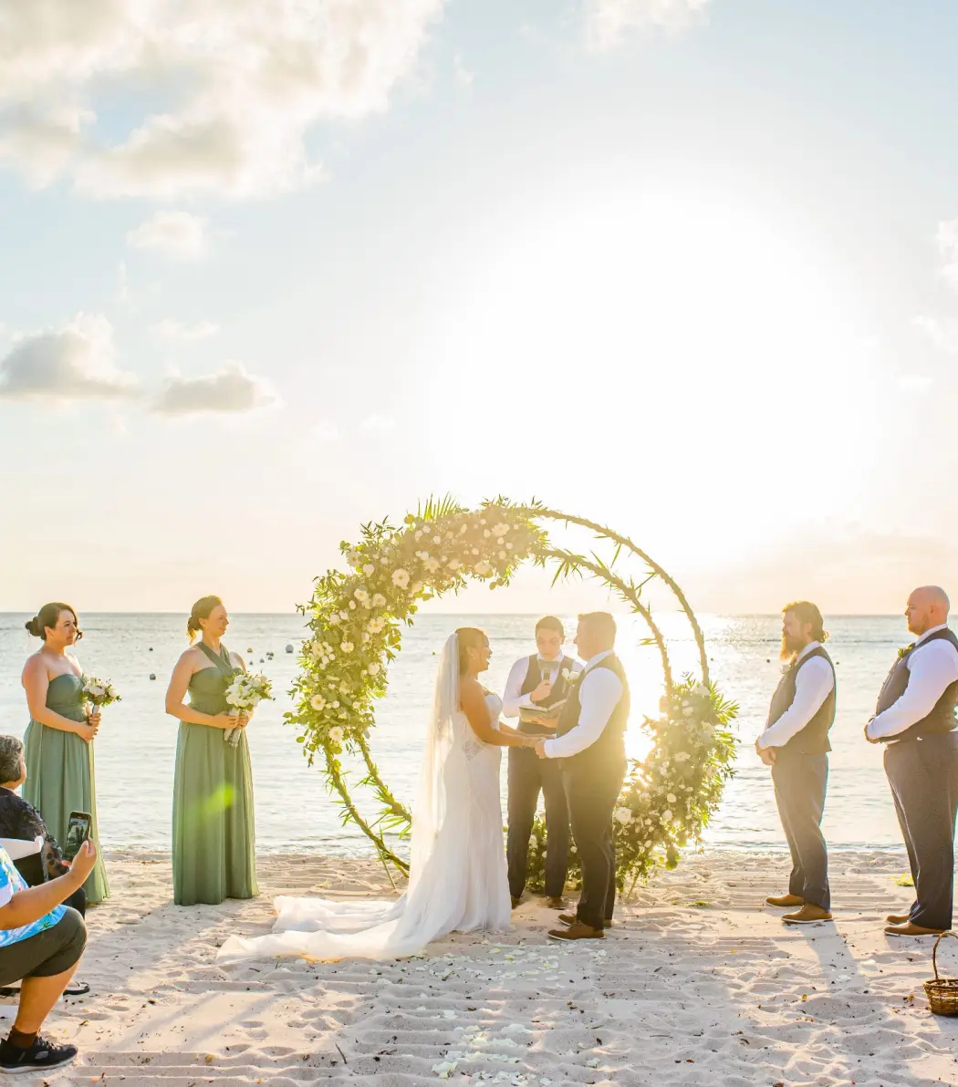 Beachfront wedding ceremony under a circular floral arch at Dreams Cozumel, Cozumel