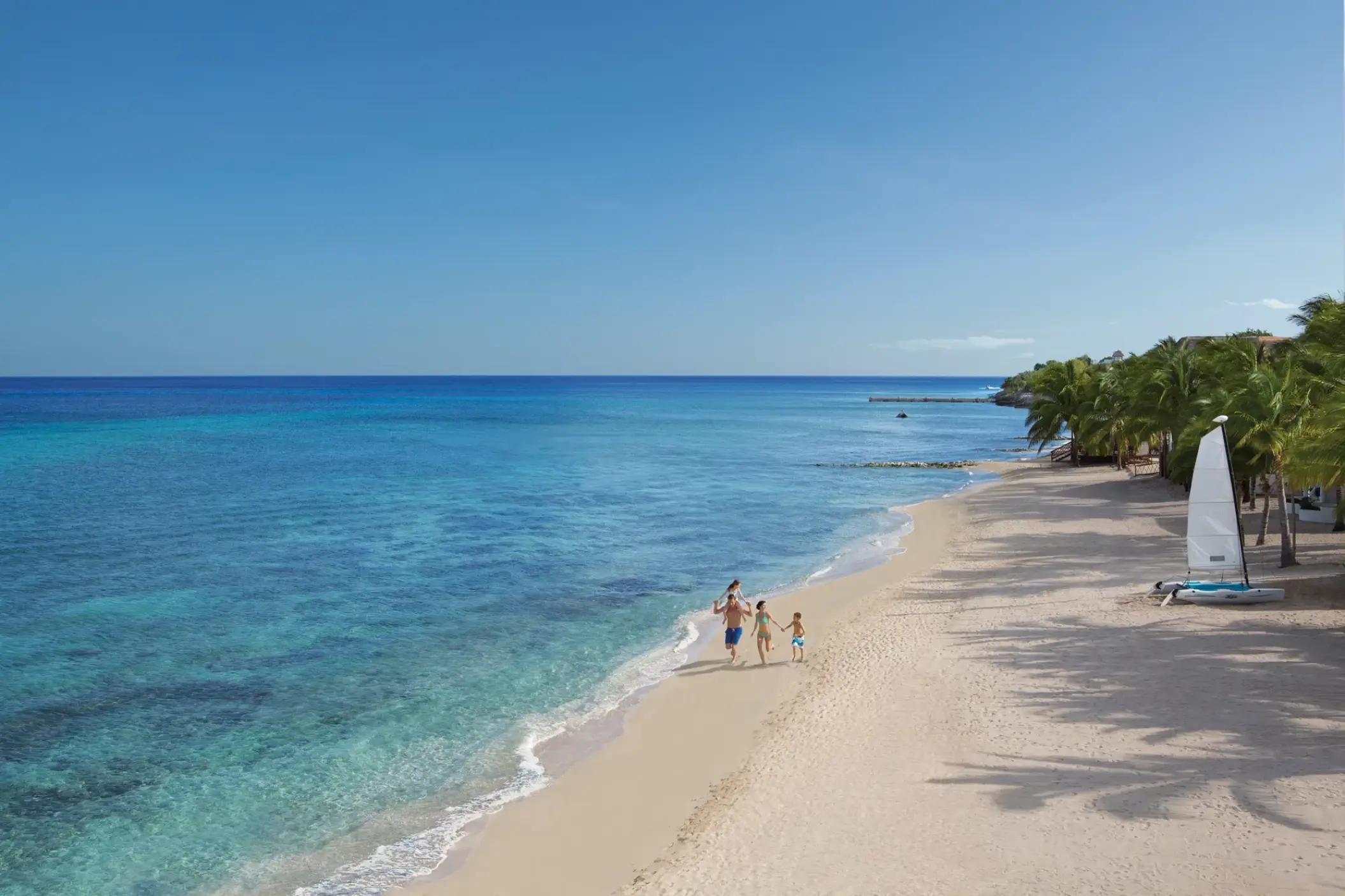 Family walking along the white sand beach at Dreams Cozumel, Cozumel