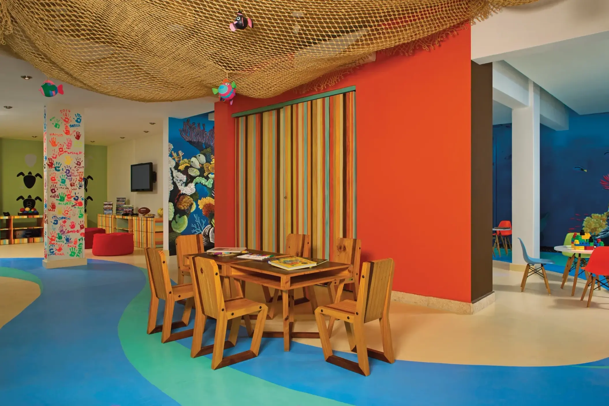 Colorful kids club with wooden activity tables and marine wall murals at Dreams Cozumel, Cozumel