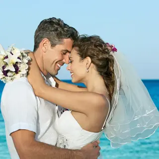 Bride and groom embracing by the turquoise ocean at Dreams Cozumel