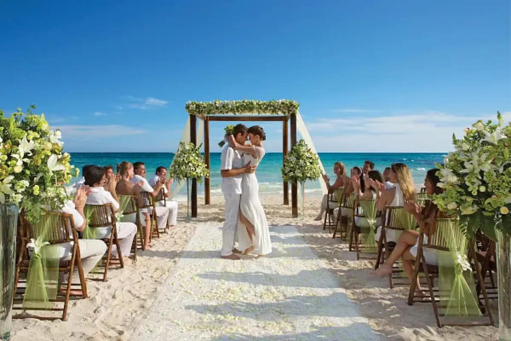 Beach ceremony at Dreams Cozumel Cape, Cozumel with a couple at a wooden arch and seated guests