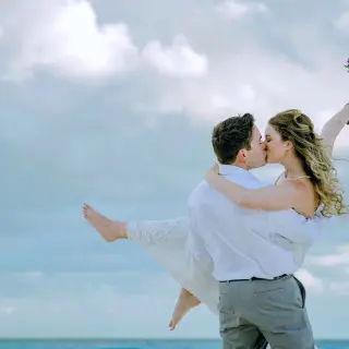 Groom carrying his bride while kissing on the beach at Dreams Cozumel, Cozumel