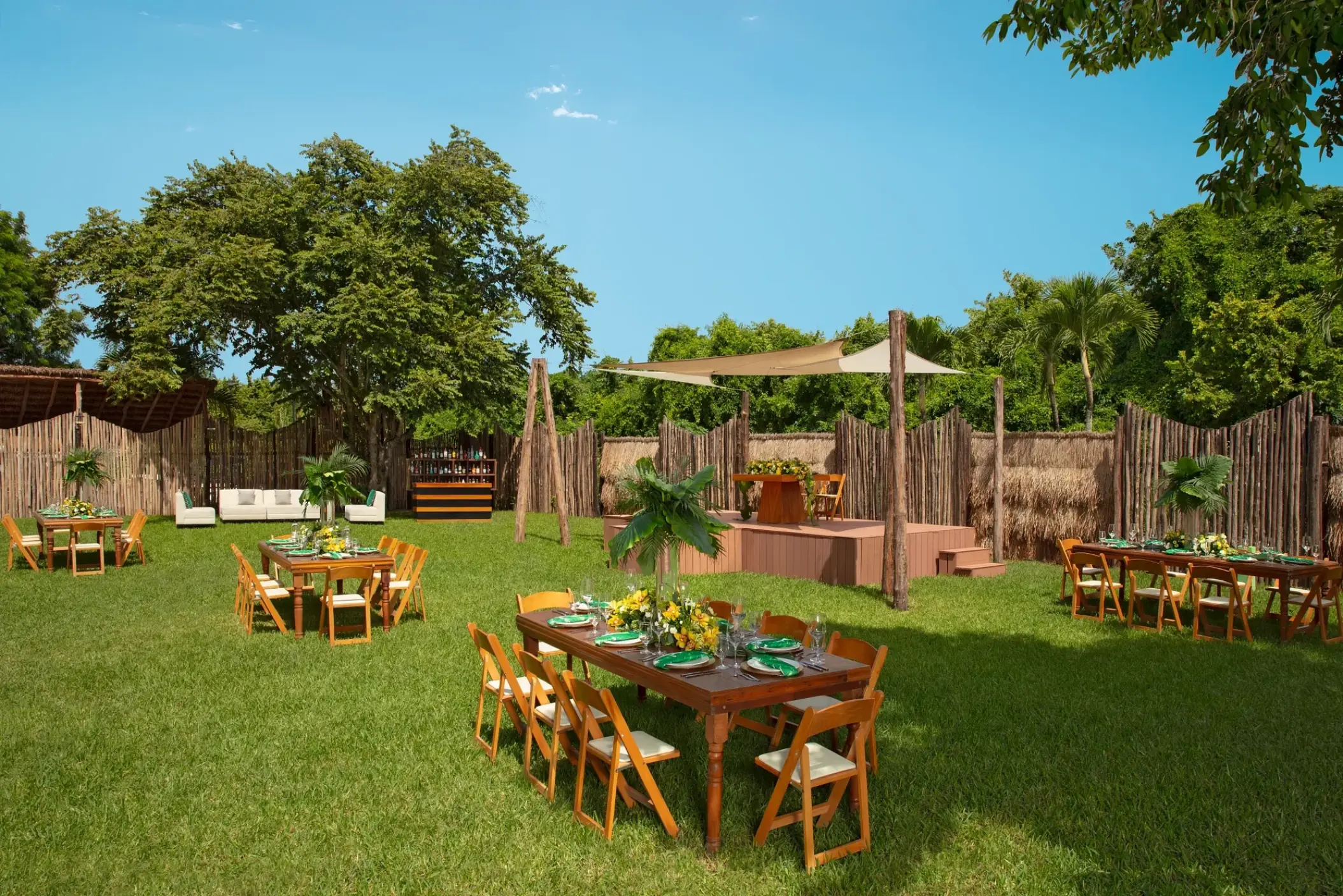 Garden wedding reception with wooden tables and a platform stage at Dreams Cozumel, Cozumel