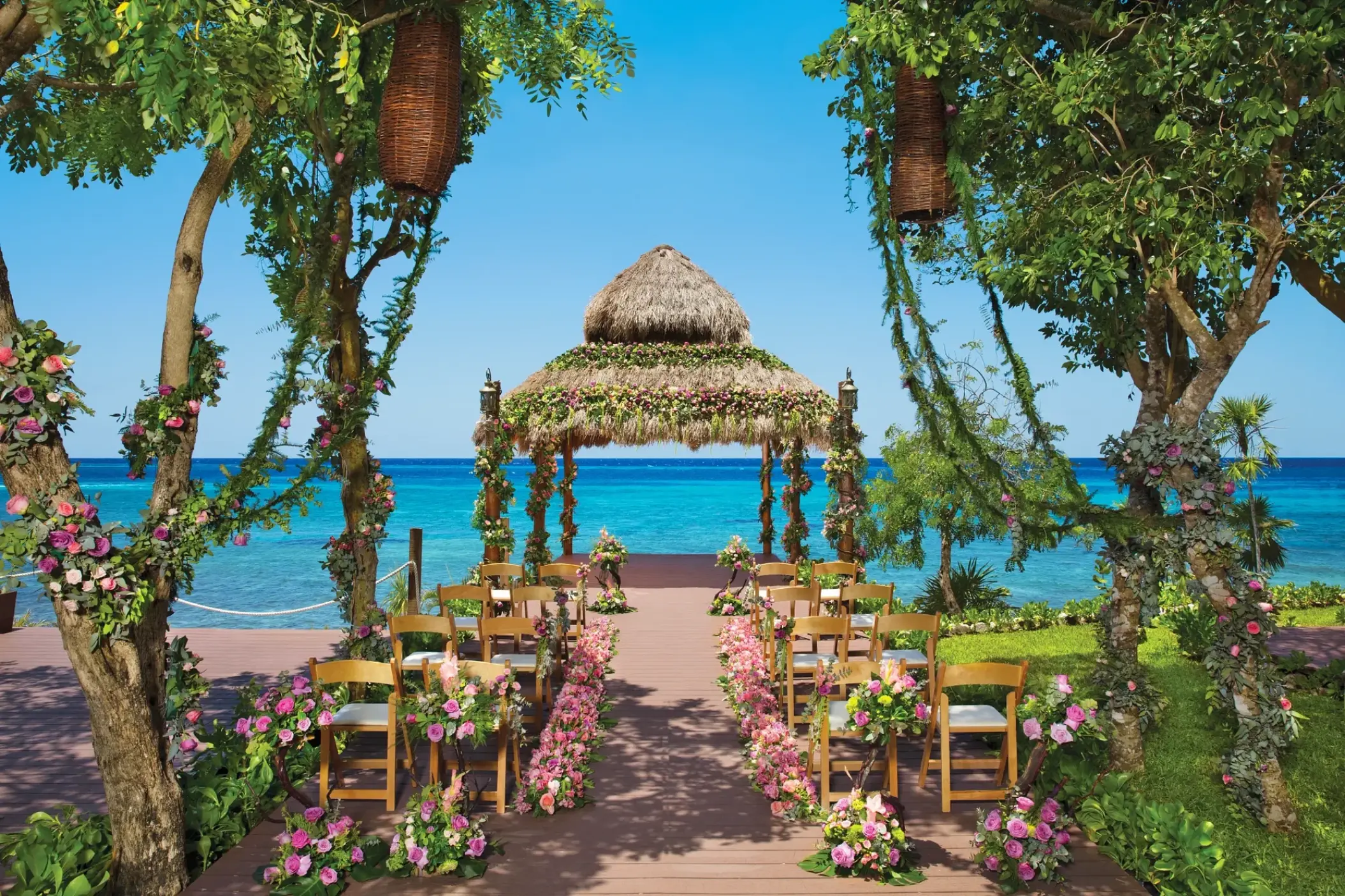 Thatched gazebo wedding ceremony with floral decor at Dreams Cozumel, Cozumel