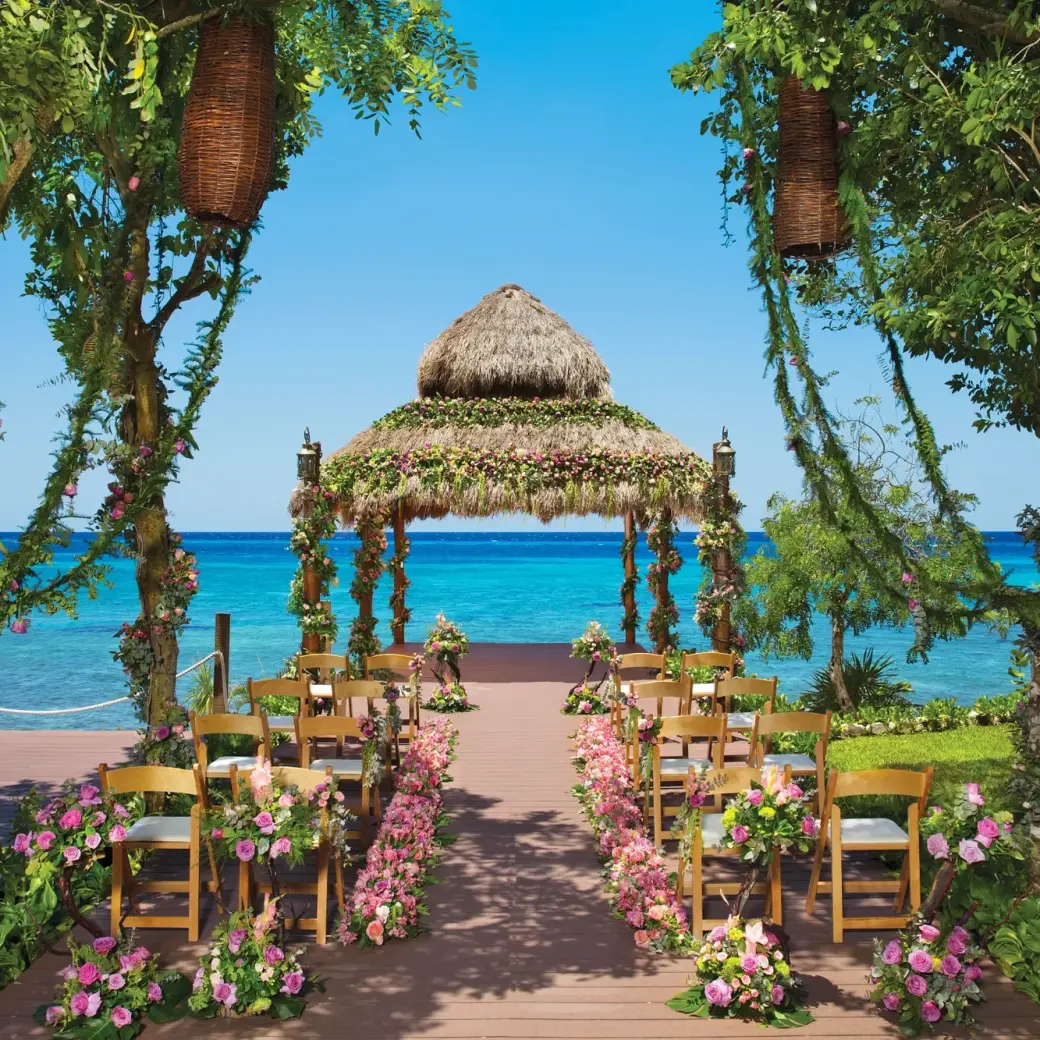 Thatched gazebo wedding ceremony with floral decor at Dreams Cozumel, Cozumel