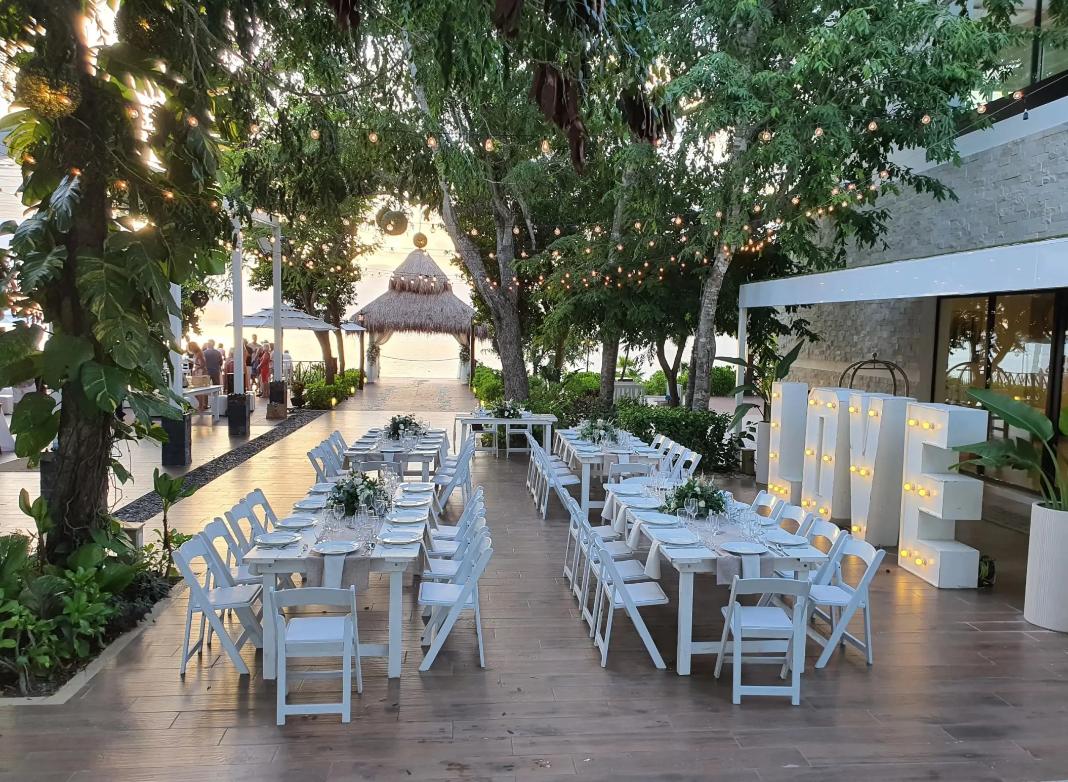 Outdoor wedding reception setup with white tables and large light-up LOVE letters at Dreams Cozumel, Cozumel
