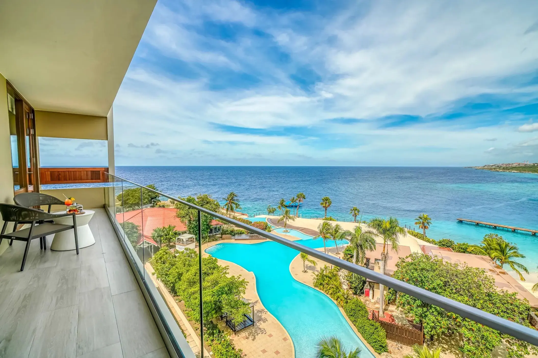 Private balcony of a suite at Dreams Curacao overlooking the resort pool and turquoise ocean, Willemstad
