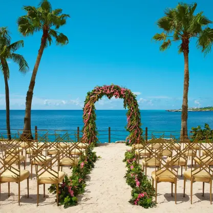 Beachfront wedding ceremony with floral arch and gold chairs at Dreams Curacao, Willemstad