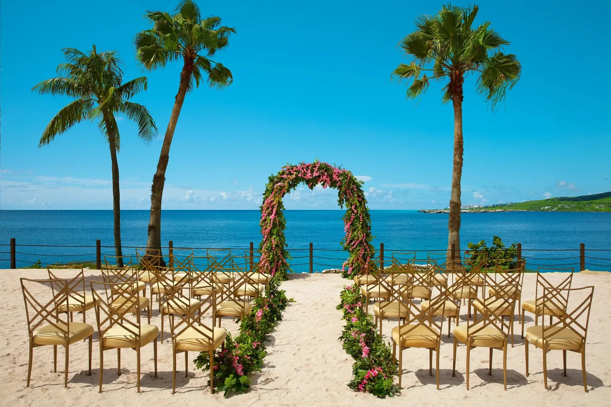 Beachfront wedding ceremony with floral arch and gold chairs at Dreams Curacao, Willemstad