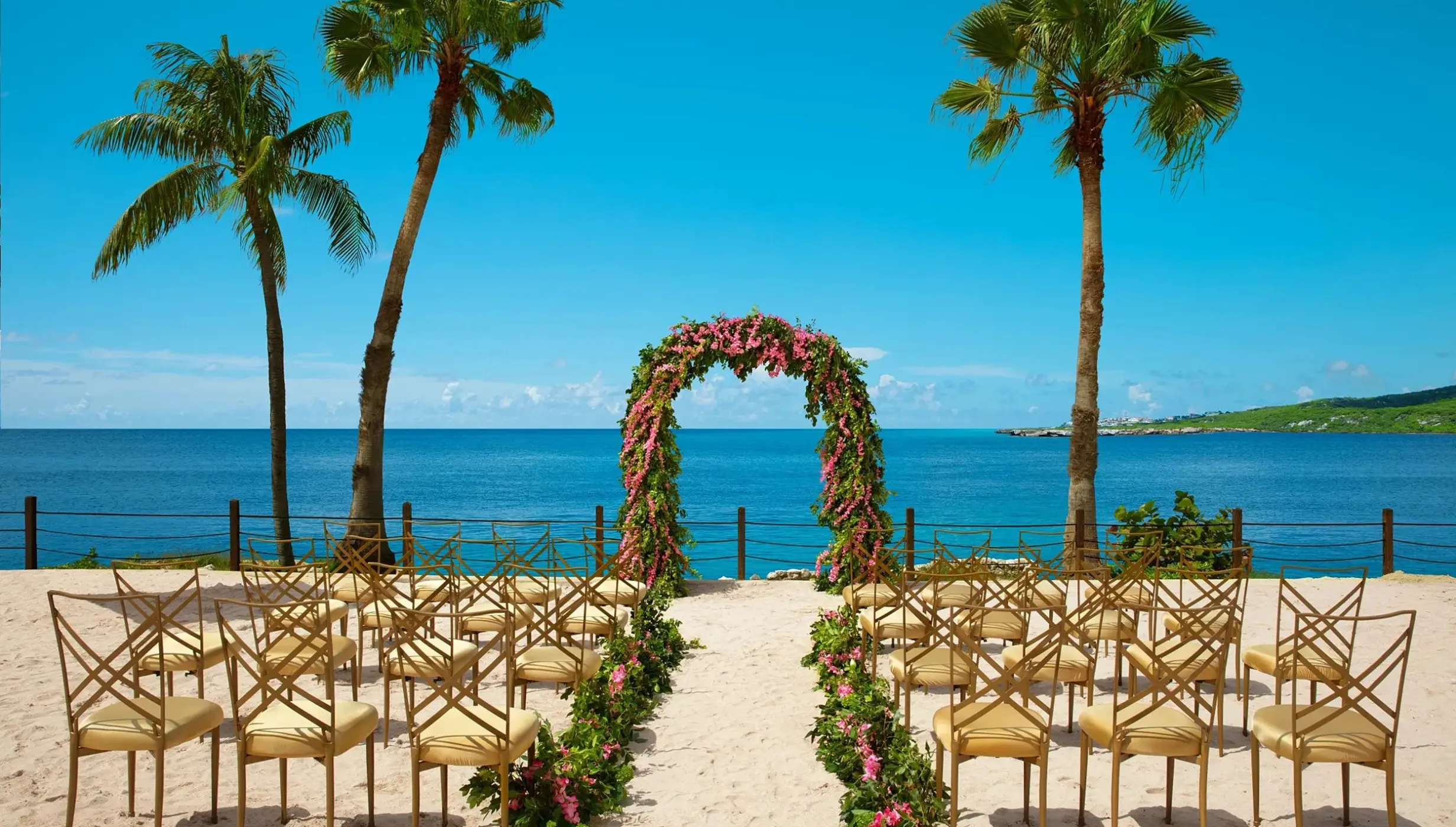 Beachfront wedding ceremony with floral arch and gold chairs at Dreams Curacao, Willemstad