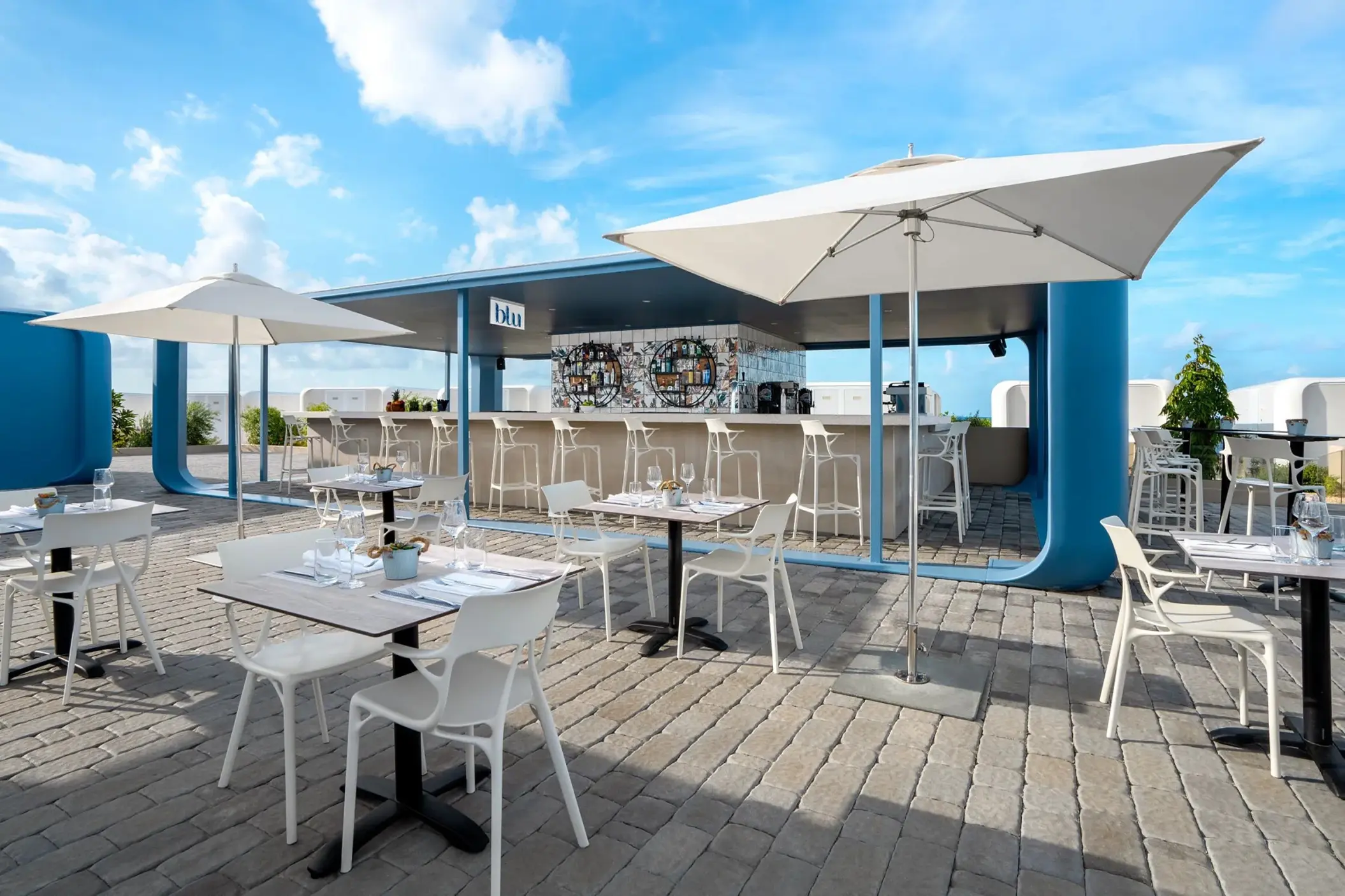 Blu Bar outdoor patio with white tables and umbrellas at Dreams Curacao, Willemstad