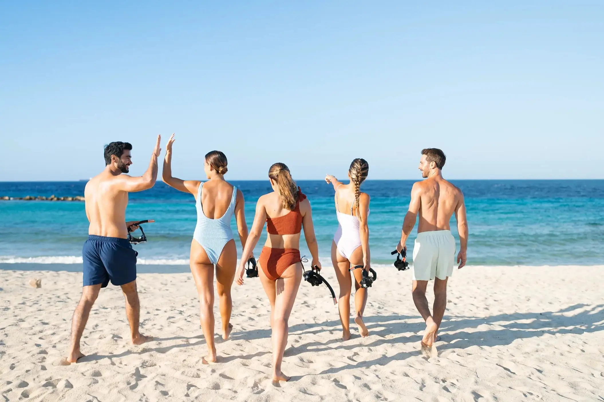 Friends carrying snorkel gear on the beach at Dreams Curacao, Willemstad