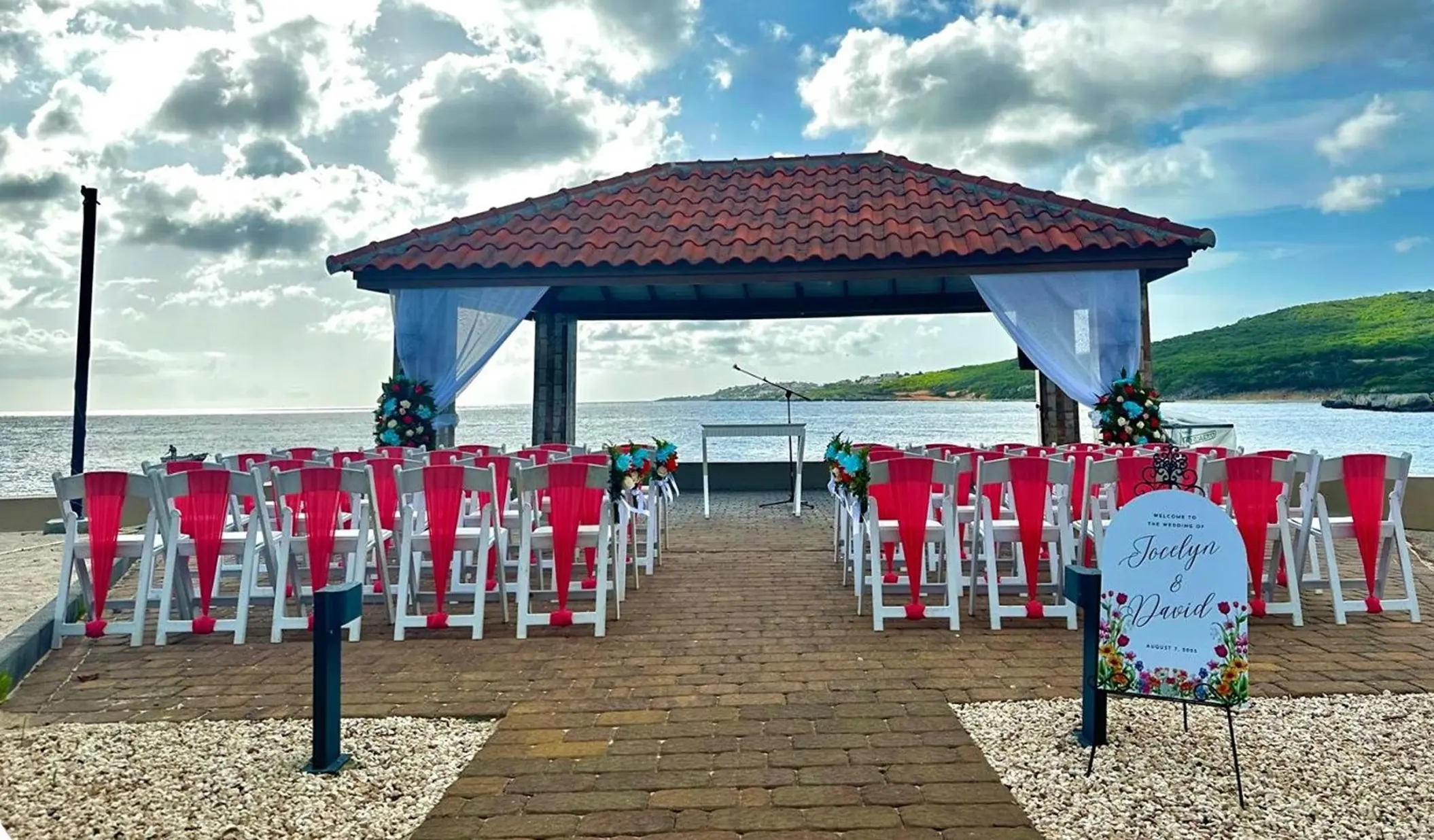 Waterfront gazebo wedding ceremony with red sashes at Dreams Curacao, Willemstad