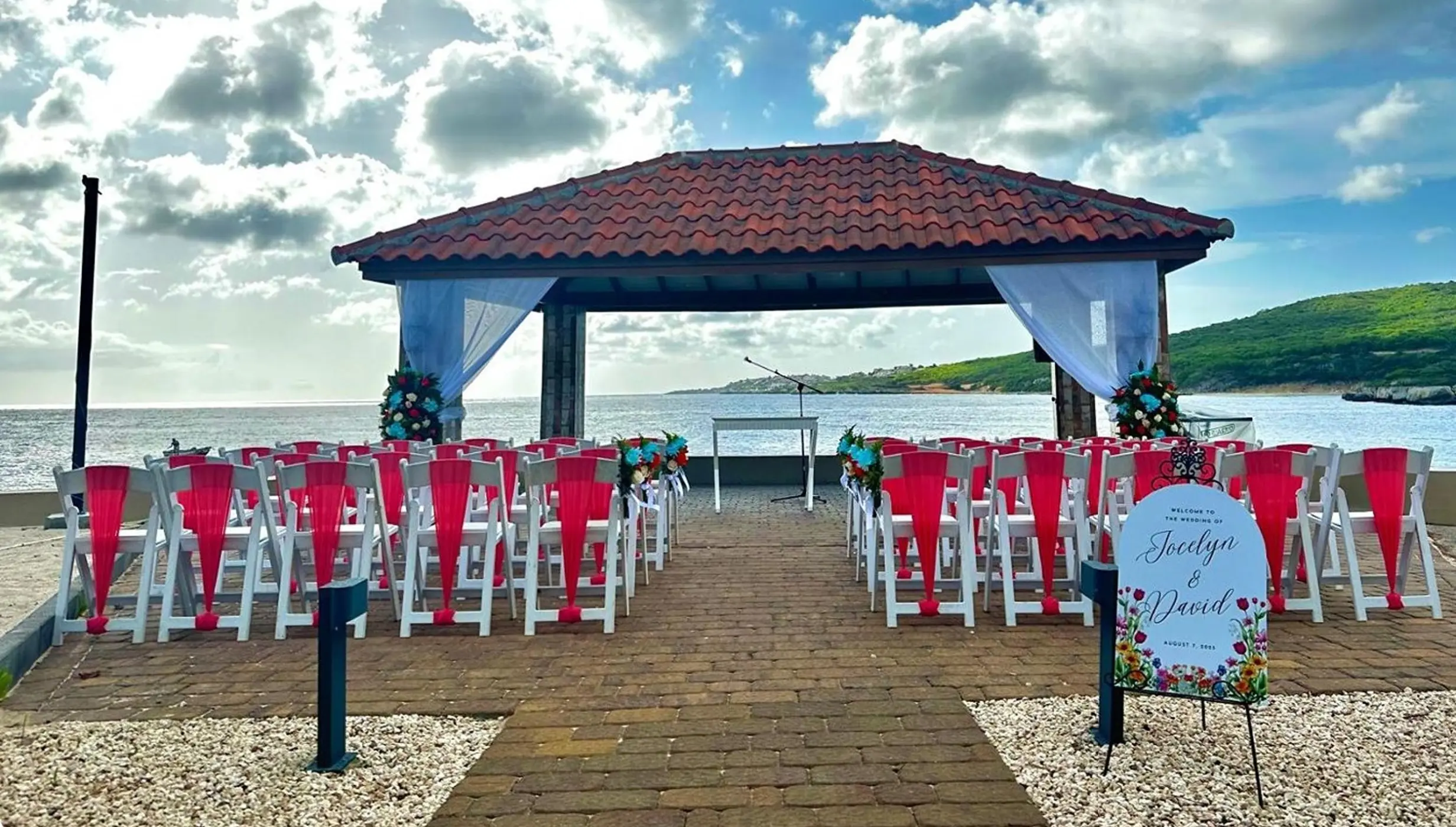 Waterfront gazebo wedding ceremony with red sashes at Dreams Curacao, Willemstad