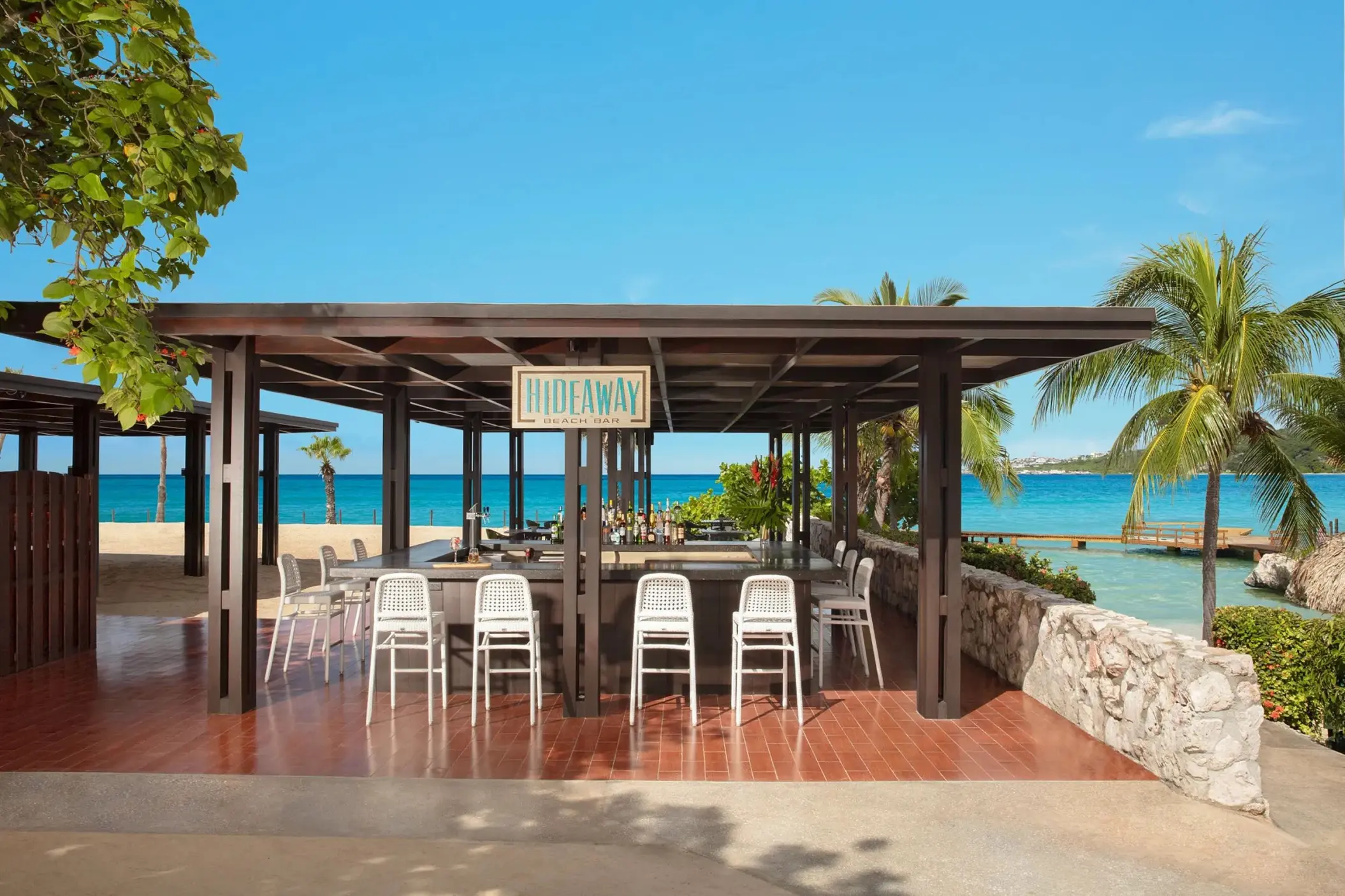 Hideaway beach bar with white stools and ocean views at Dreams Curacao, Willemstad