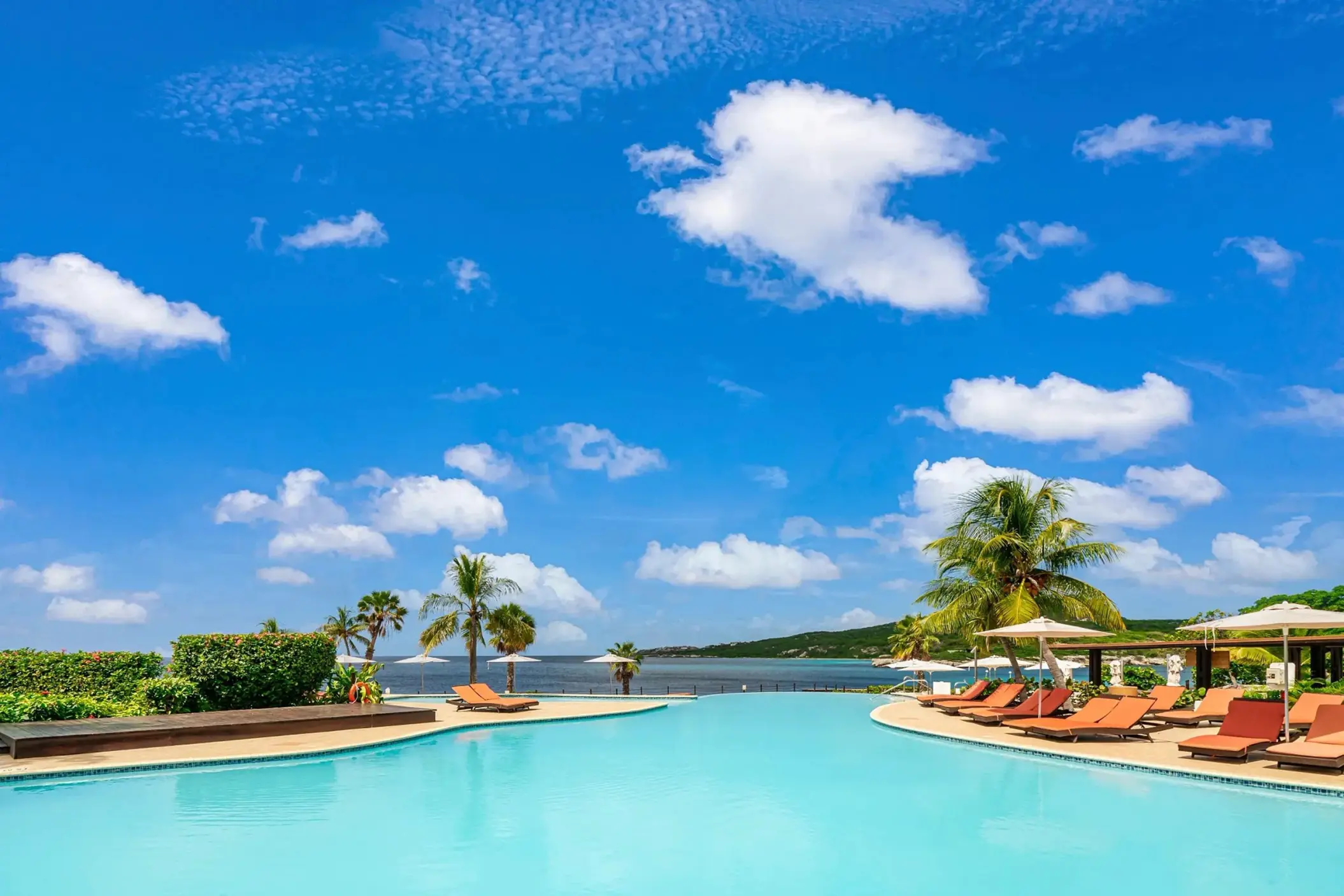 Infinity pool with orange lounge chairs at Dreams Curacao, Willemstad