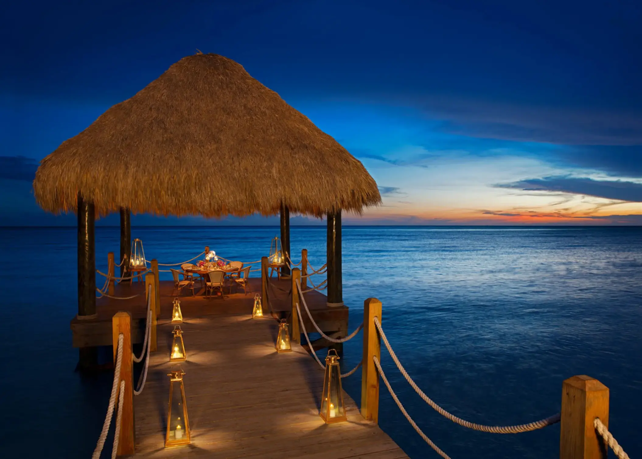 Private dinner setup under a thatched gazebo on the pier at Dreams Dominicus, La Romana