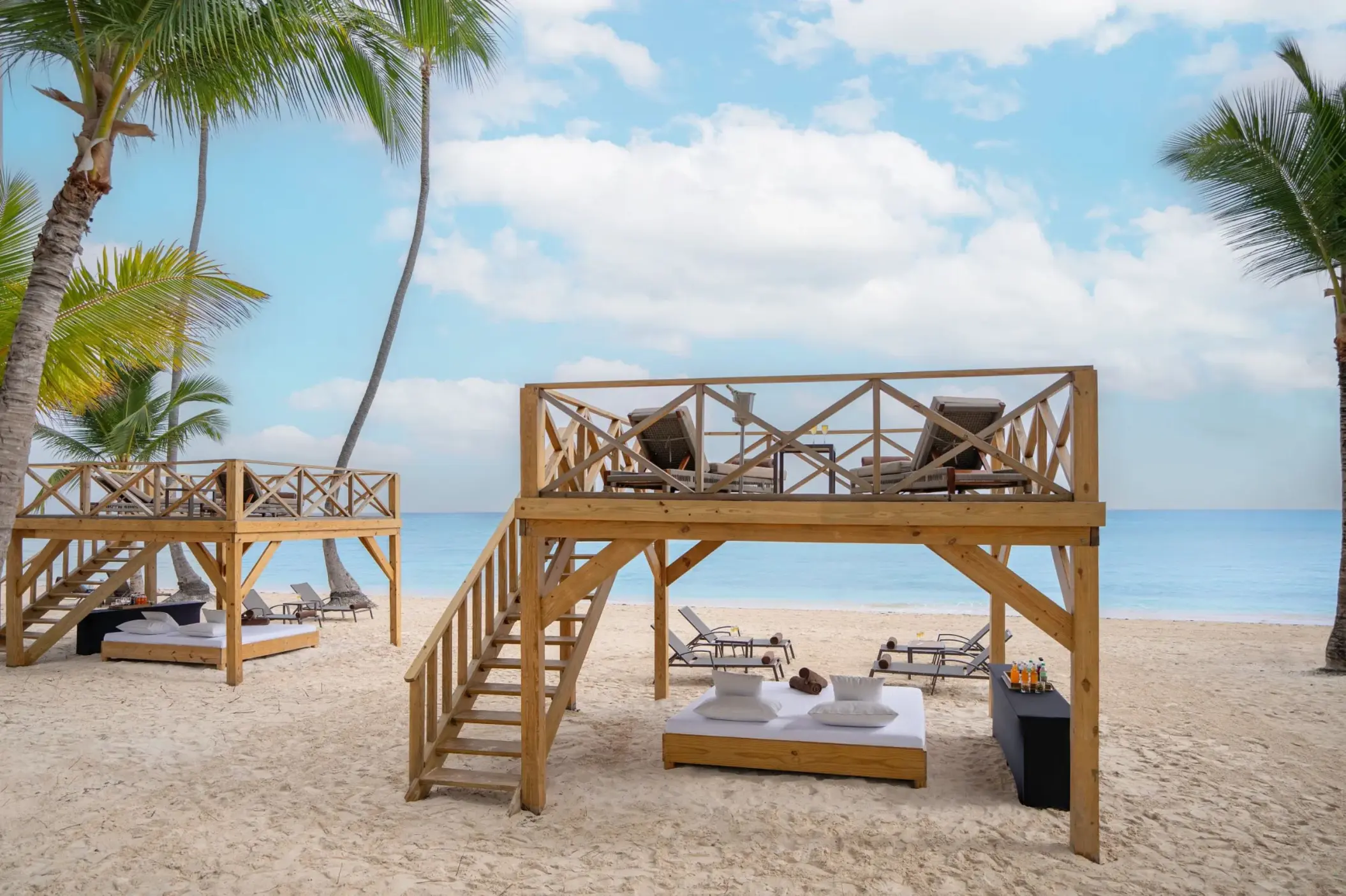 Two-story wooden beach cabanas with Bali beds on the sand at Dreams Flora, Punta Cana