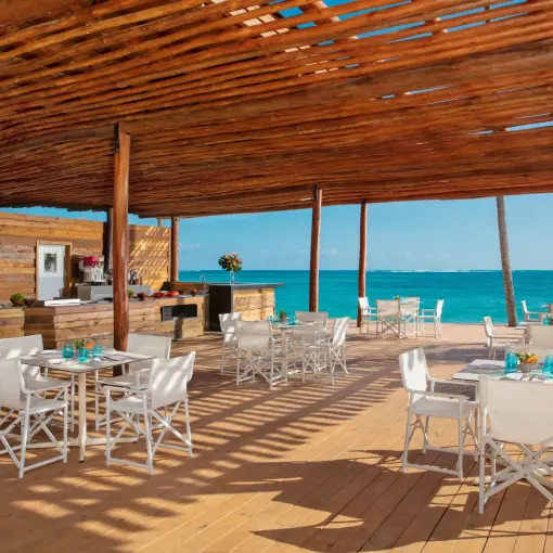 Barefoot Grill beachfront dining area under a wooden pergola at Dreams Flora, Punta Cana