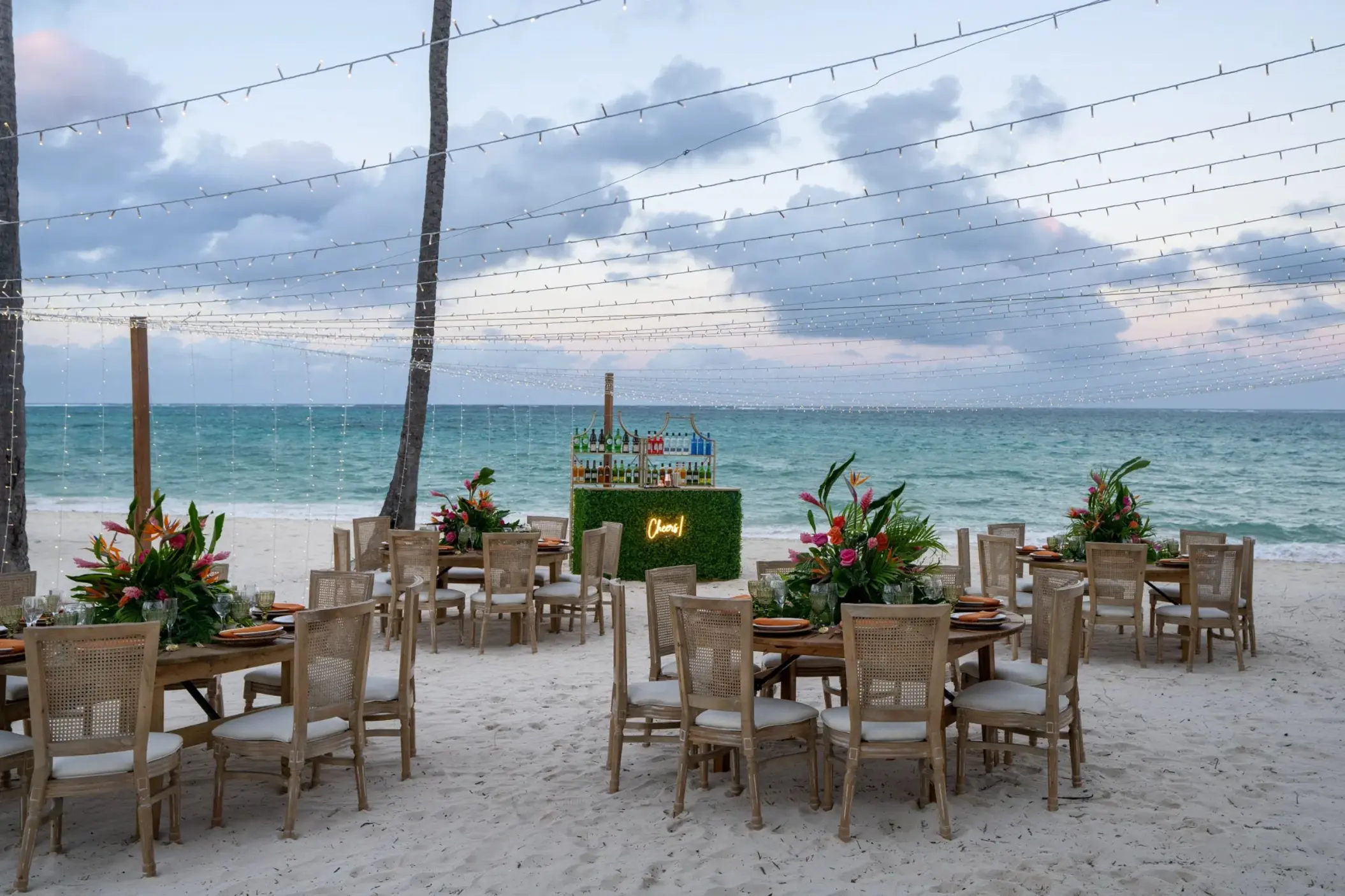 Beach wedding reception with string lights and floral centerpieces at Dreams Flora, Punta Cana