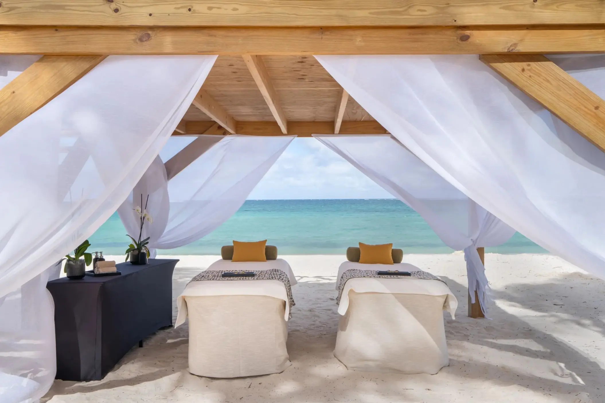 Beachfront massage cabana with two tables under white curtains at Dreams Flora, Punta Cana