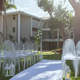 Garden wedding ceremony with clear chairs and white floral arrangements at Dreams Flora, Punta Cana
