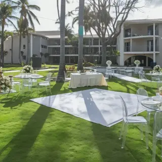 Garden wedding reception at Dreams Flora, Punta Cana with clear chairs and white floral centerpieces