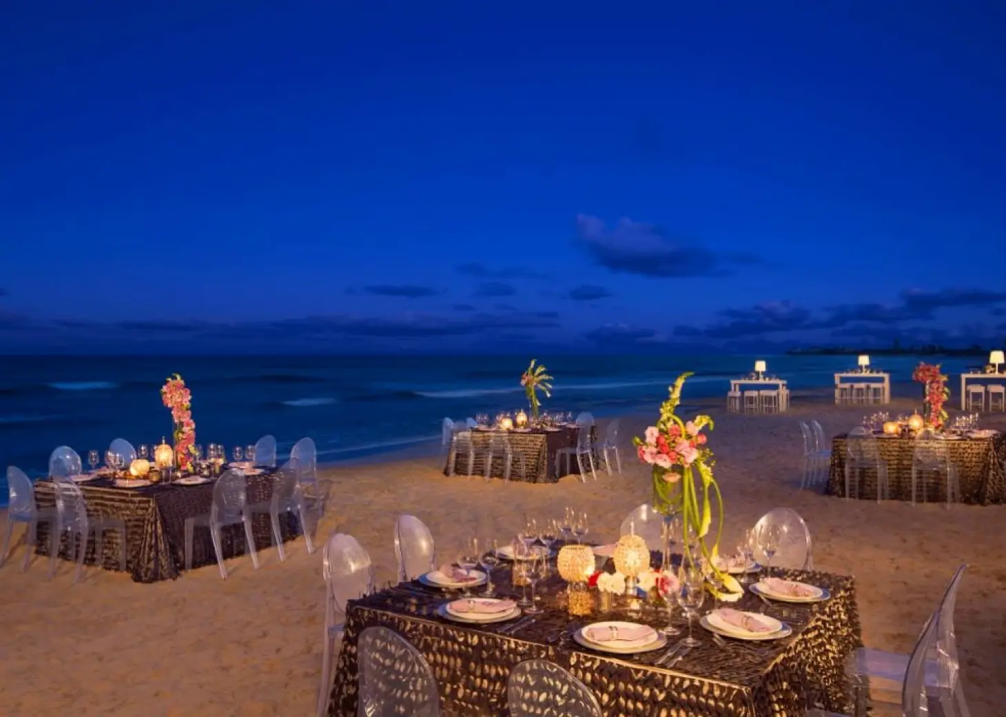Beachfront wedding reception tables under the night sky at Dreams Jade, Riviera Maya