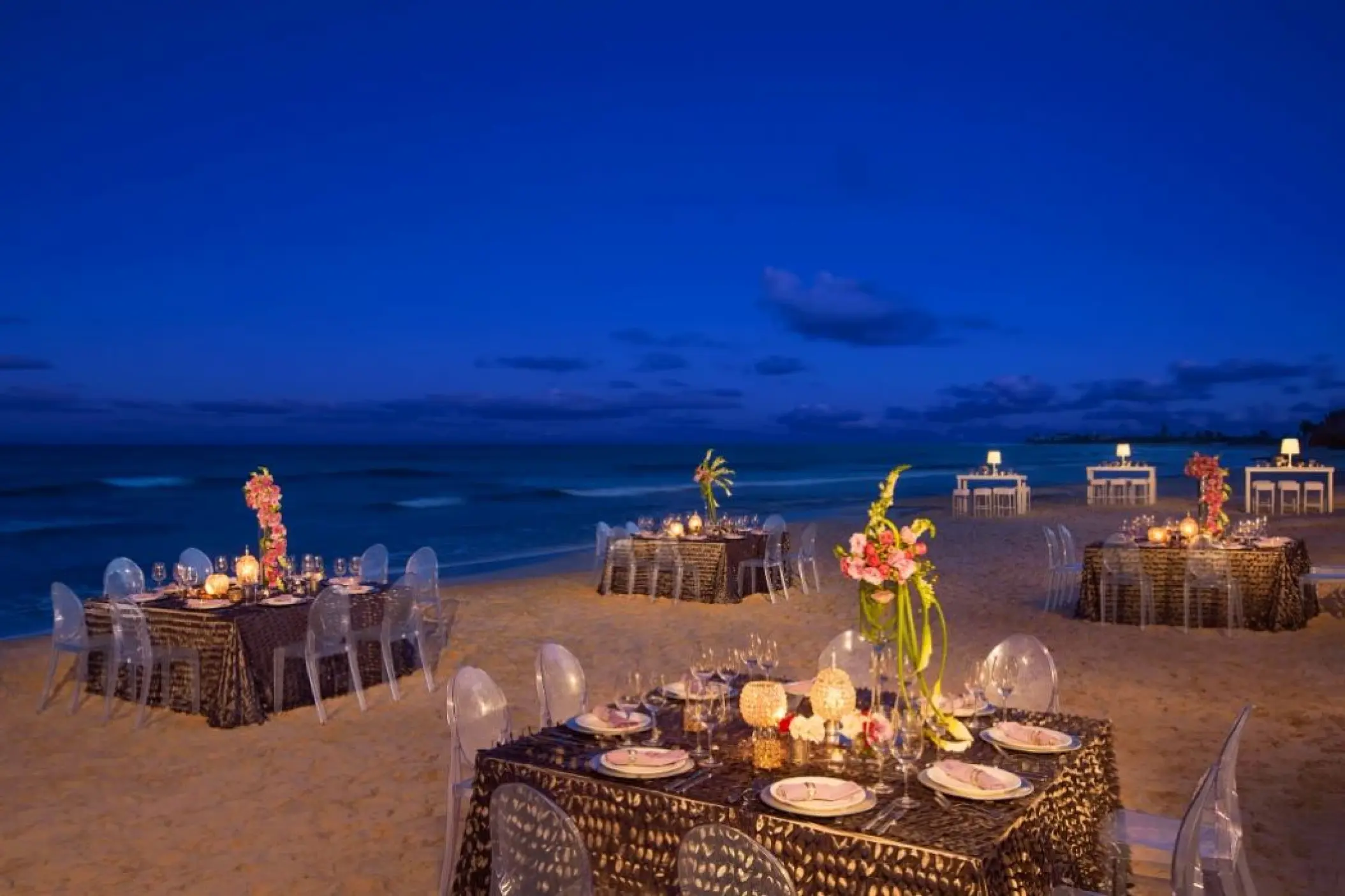 Beachfront wedding reception tables under the night sky at Dreams Jade, Riviera Maya