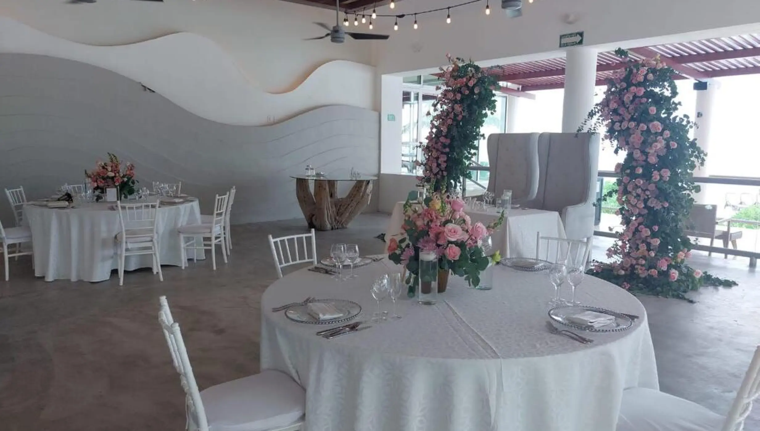 Castaways Restaurant wedding reception with pink floral arches and white tables at Dreams Jade, Riviera Maya