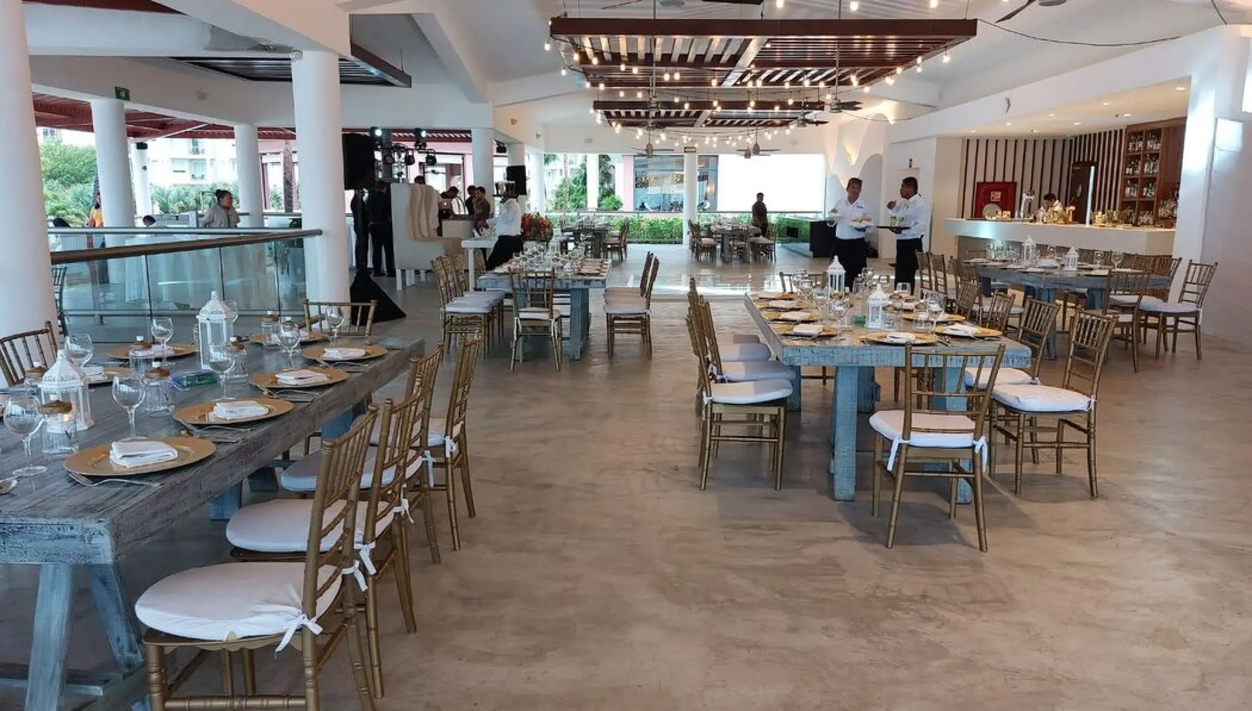 Wedding reception setup with wooden tables and string lights at Castaways restaurant, Dreams Jade