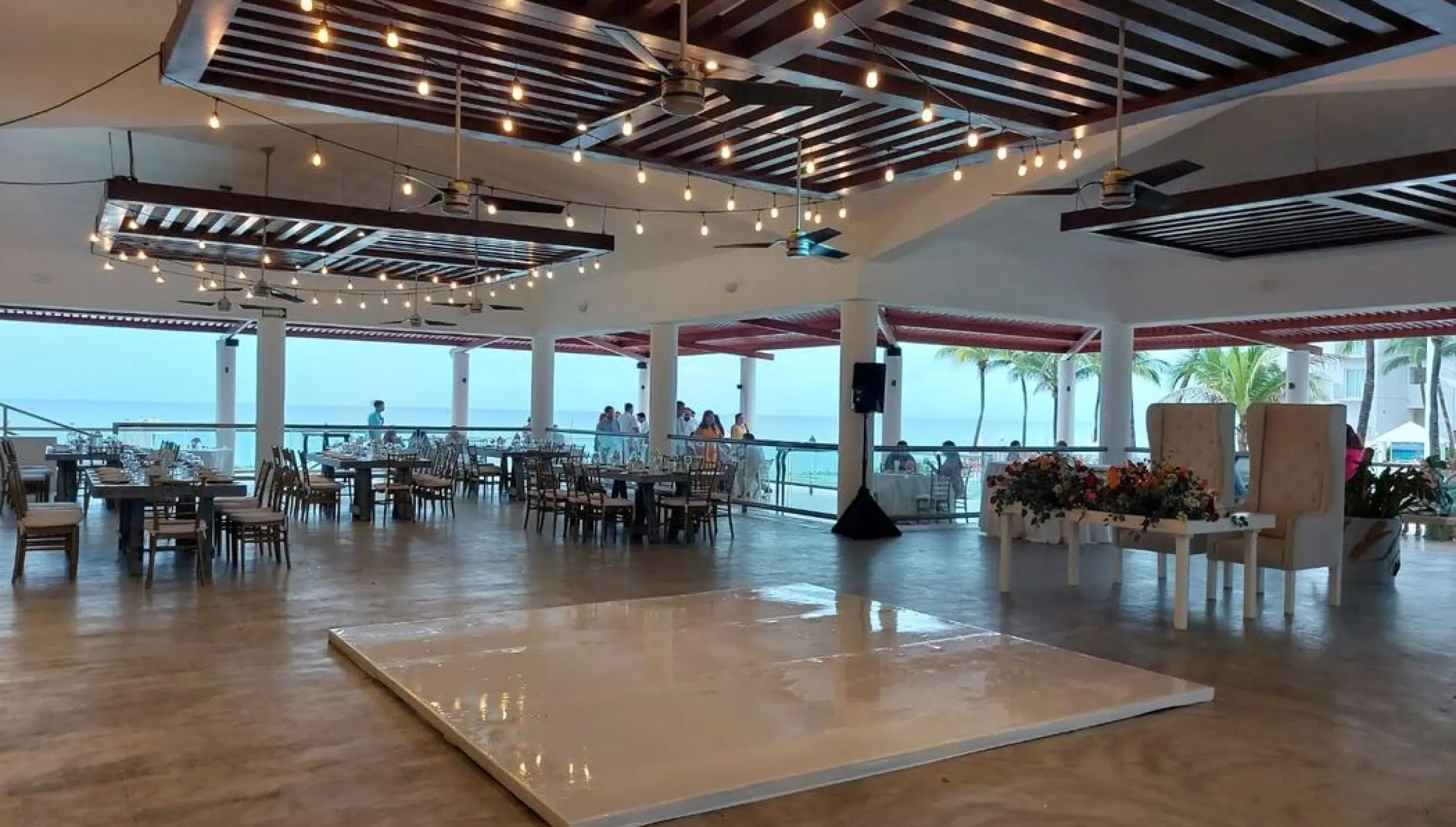Covered terrace wedding reception with a white dance floor at Dreams Jade, Riviera Maya