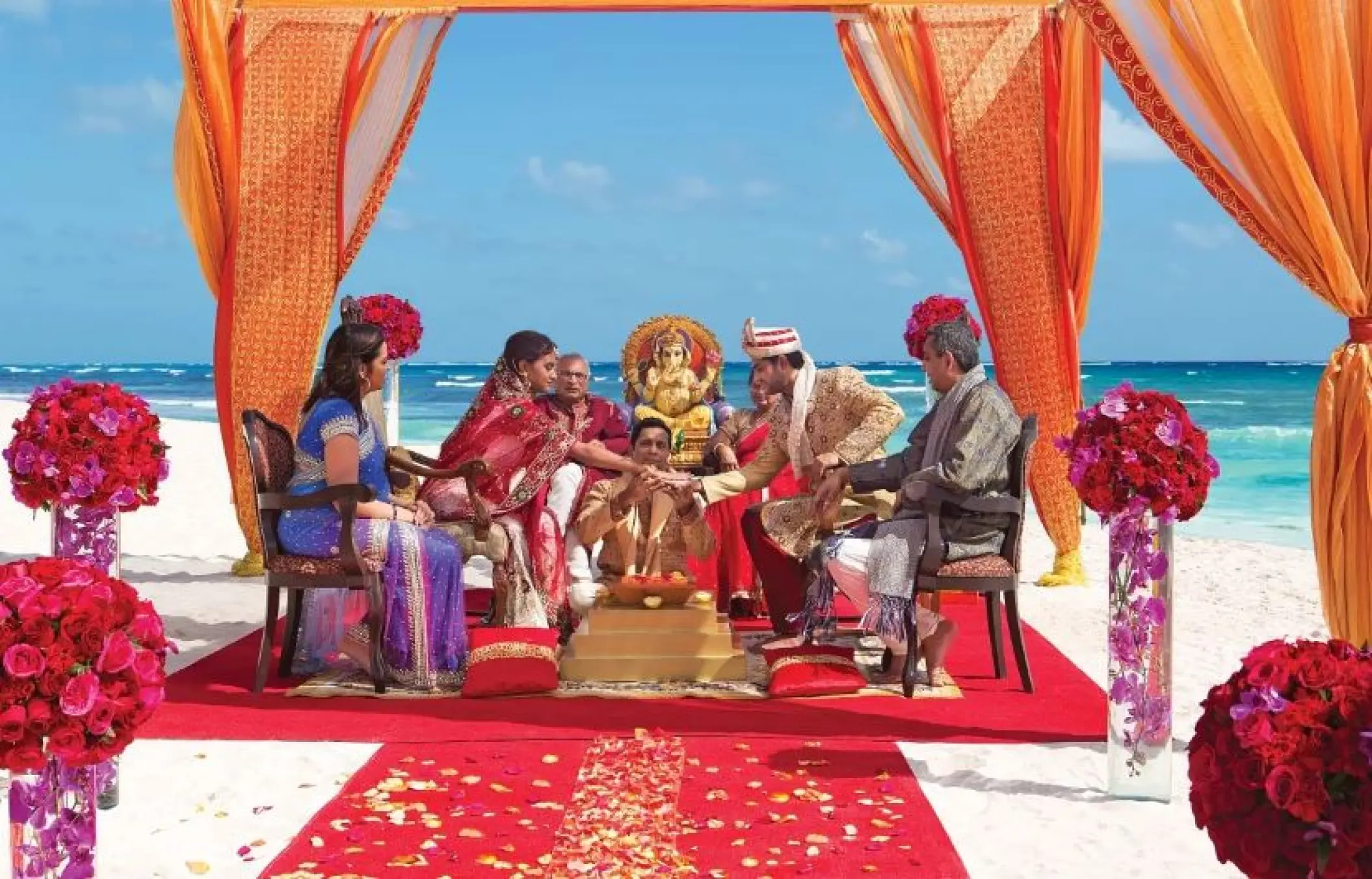 South Asian wedding ceremony under an orange mandap at Dreams Playa Esmeralda, Miches