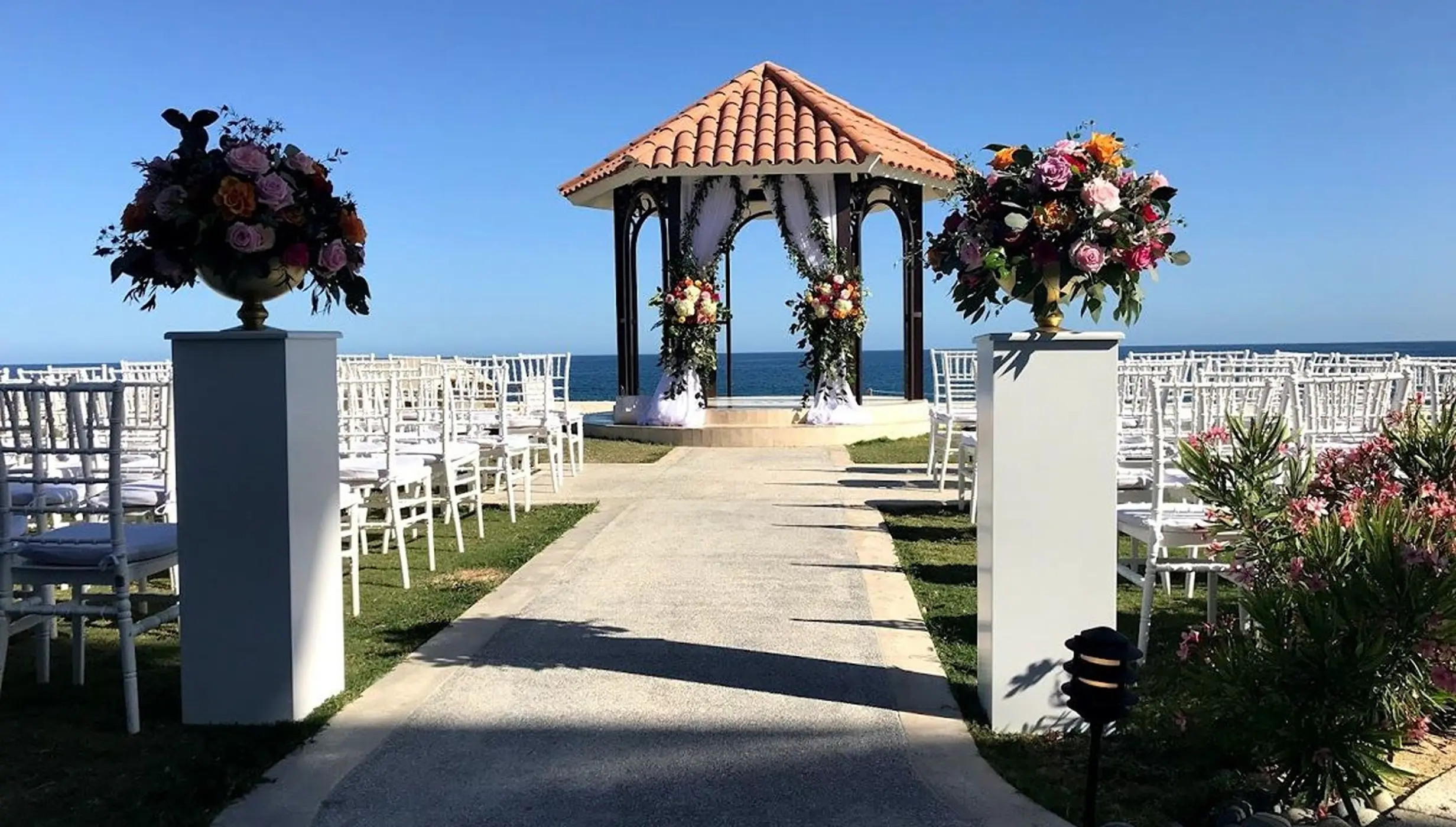 Oceanfront wedding ceremony gazebo with white chairs and floral pillars at Dreams Los Cabos, Cabo San Lucas