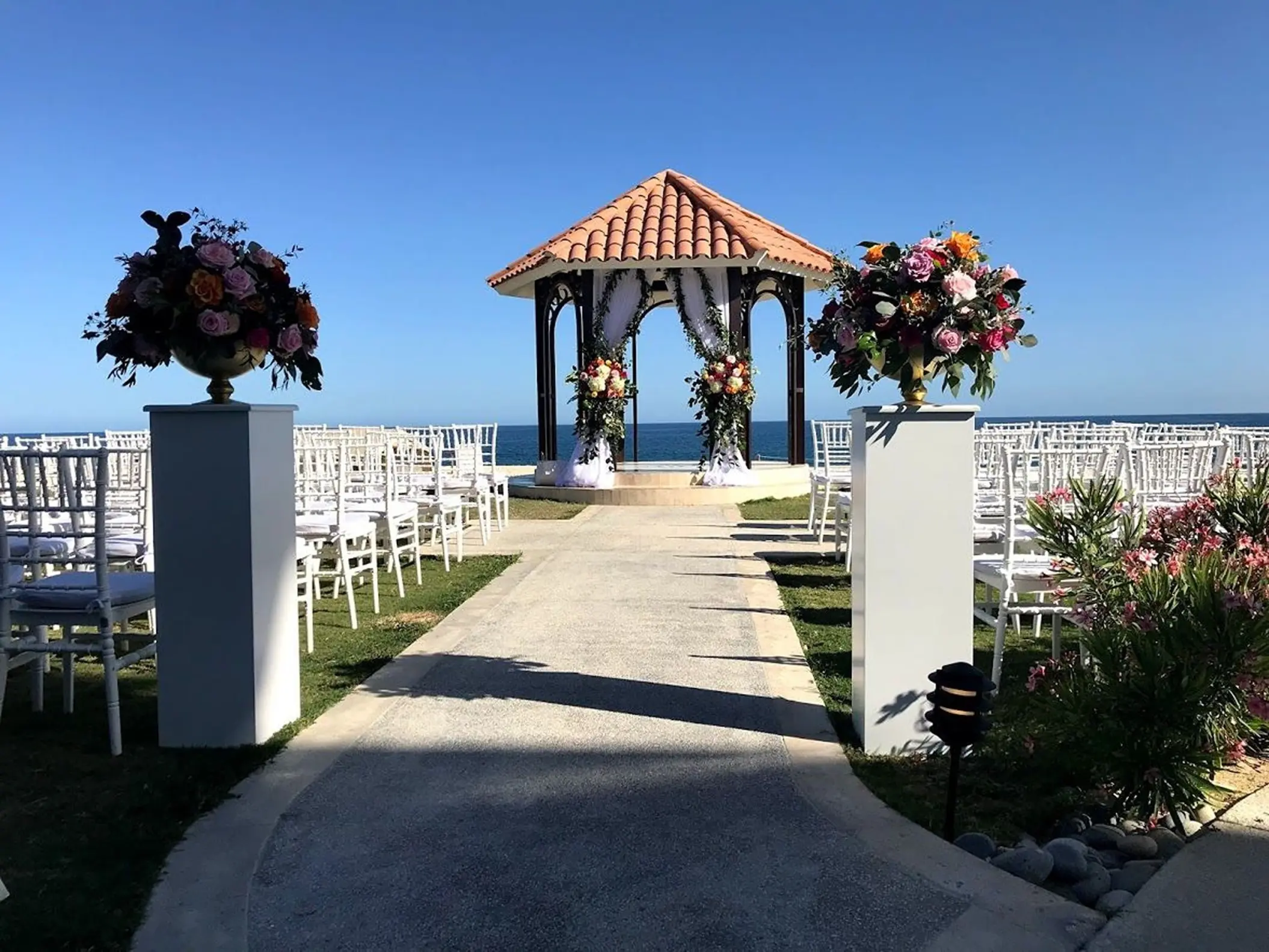 Oceanfront wedding ceremony gazebo with white chairs and floral pillars at Dreams Los Cabos, Cabo San Lucas