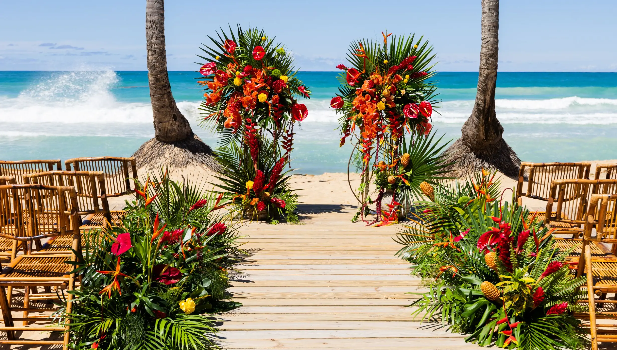 Beachfront wedding ceremony with tropical floral pillars and bamboo chairs at Dreams Macao Beach, Punta Cana