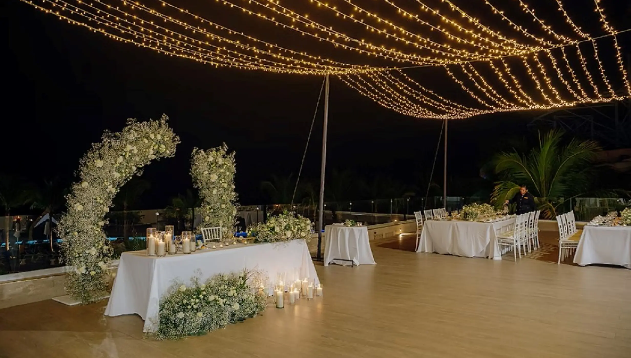 Rooftop wedding reception with floral arch and string lights at Dreams Natura, Riviera Maya