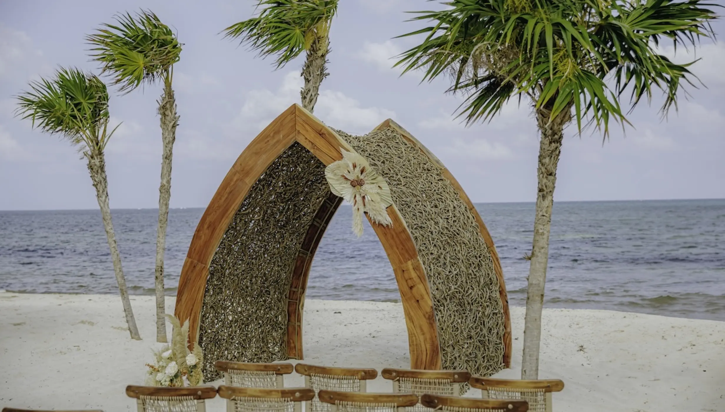 Wooden arch wedding ceremony setup on the beach at Dreams Natura, Riviera Maya