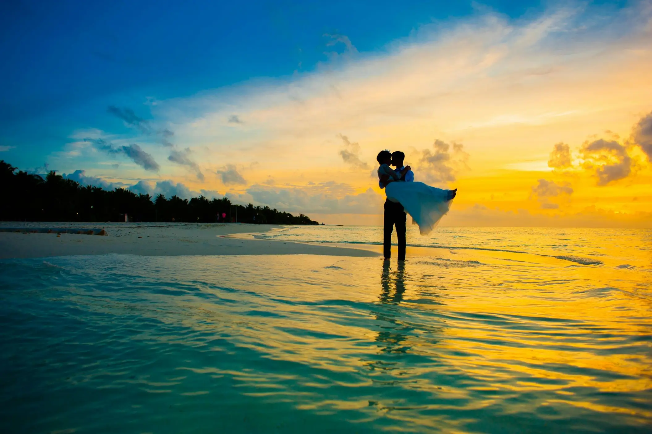 Groom carrying bride on the beach during sunset at Dreams Playa Esmeralda, Miches