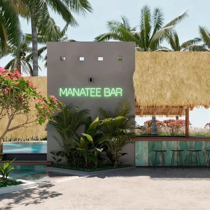 The Manatee Bar, a thatched-roof outdoor bar with a neon sign, surrounded by a pool and greenery.