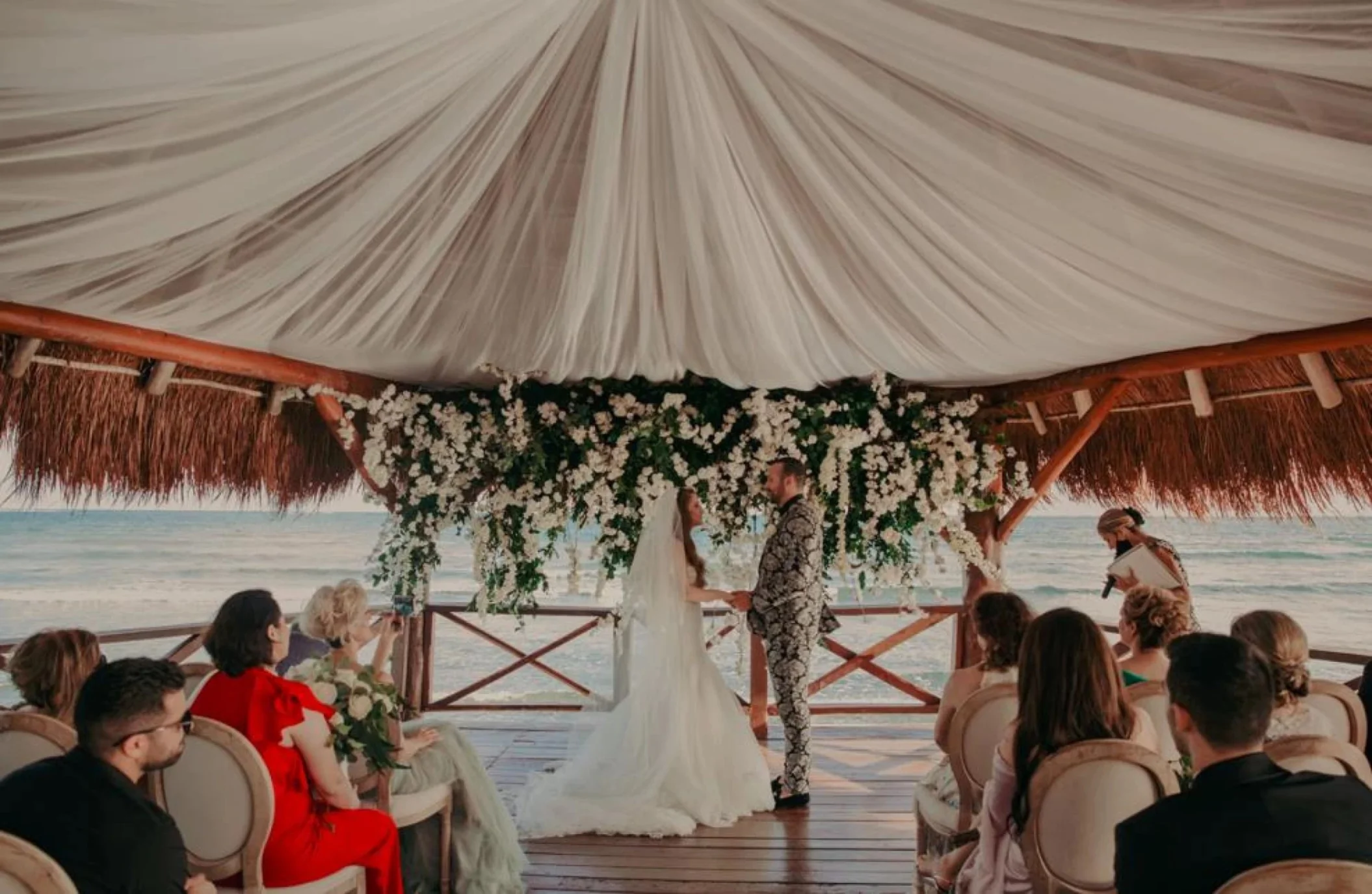 bride, groom, and guests at the overwater gazebo at Dreams Puerto Morelos Resort & Spa