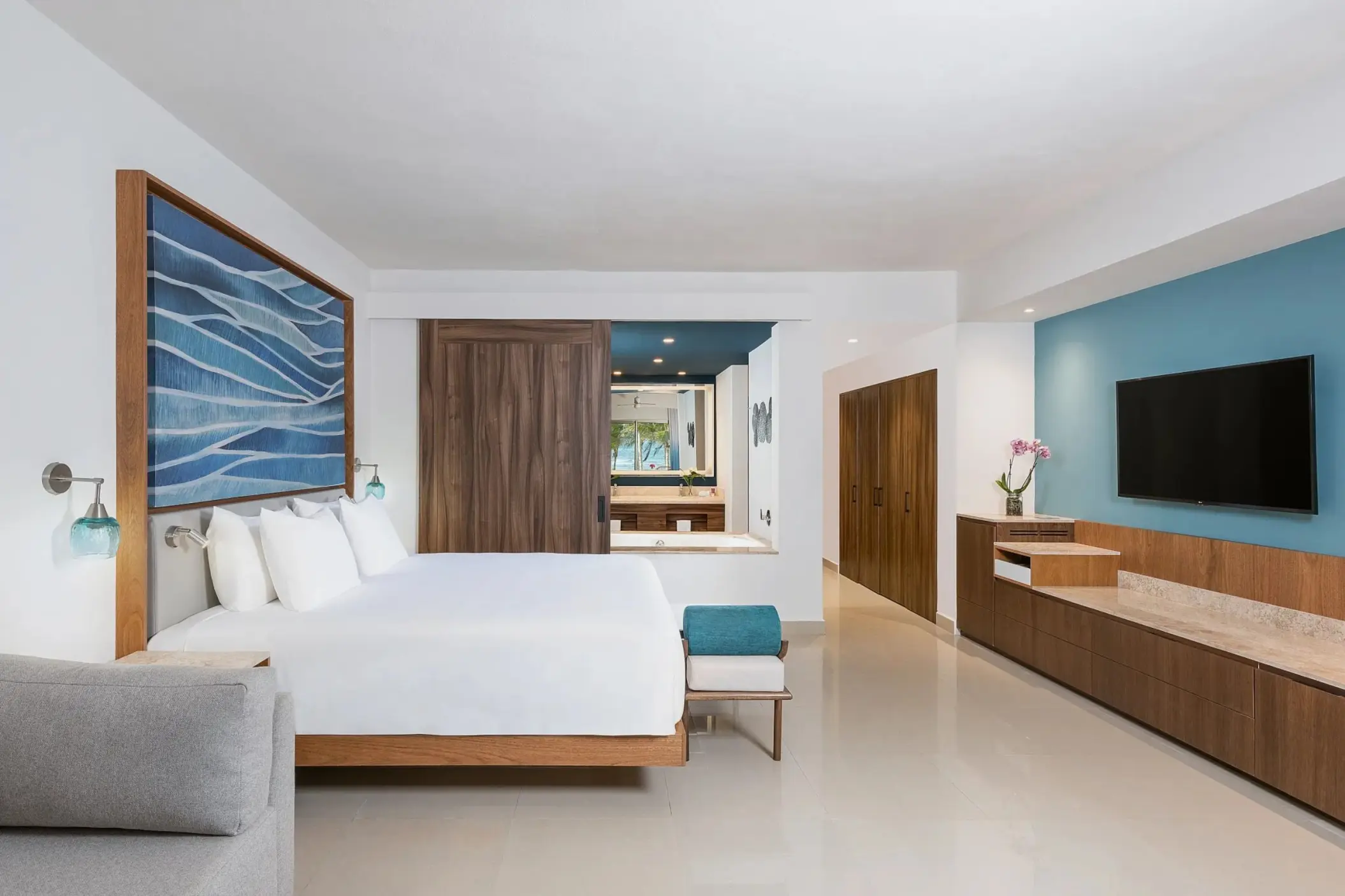 Modern king suite with blue accents and wooden furnishings at Dreams Puerto Morelos, Riviera Maya