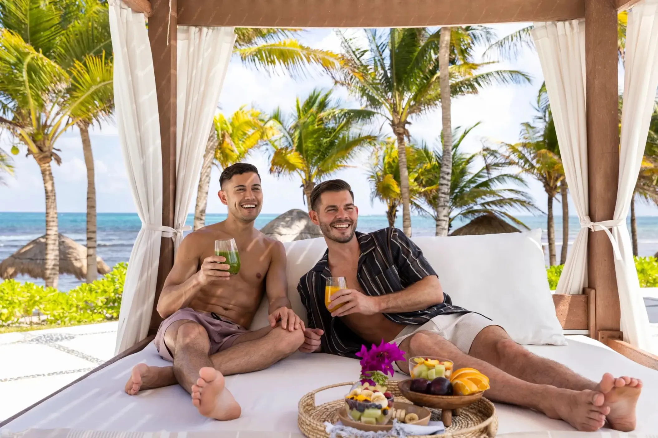 Couple relaxing in a poolside cabana with drinks and fruit at Dreams Puerto Morelos, Riviera Maya