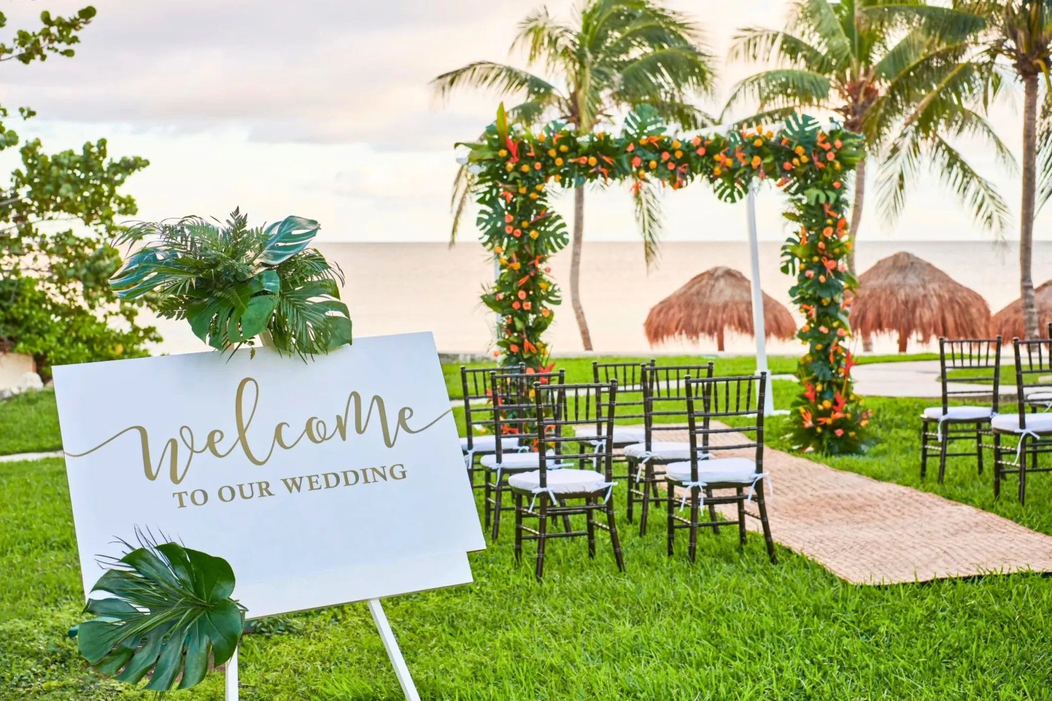 Mango Garden wedding ceremony with floral arch and welcome sign at Dreams Puerto Morelos, Riviera Maya