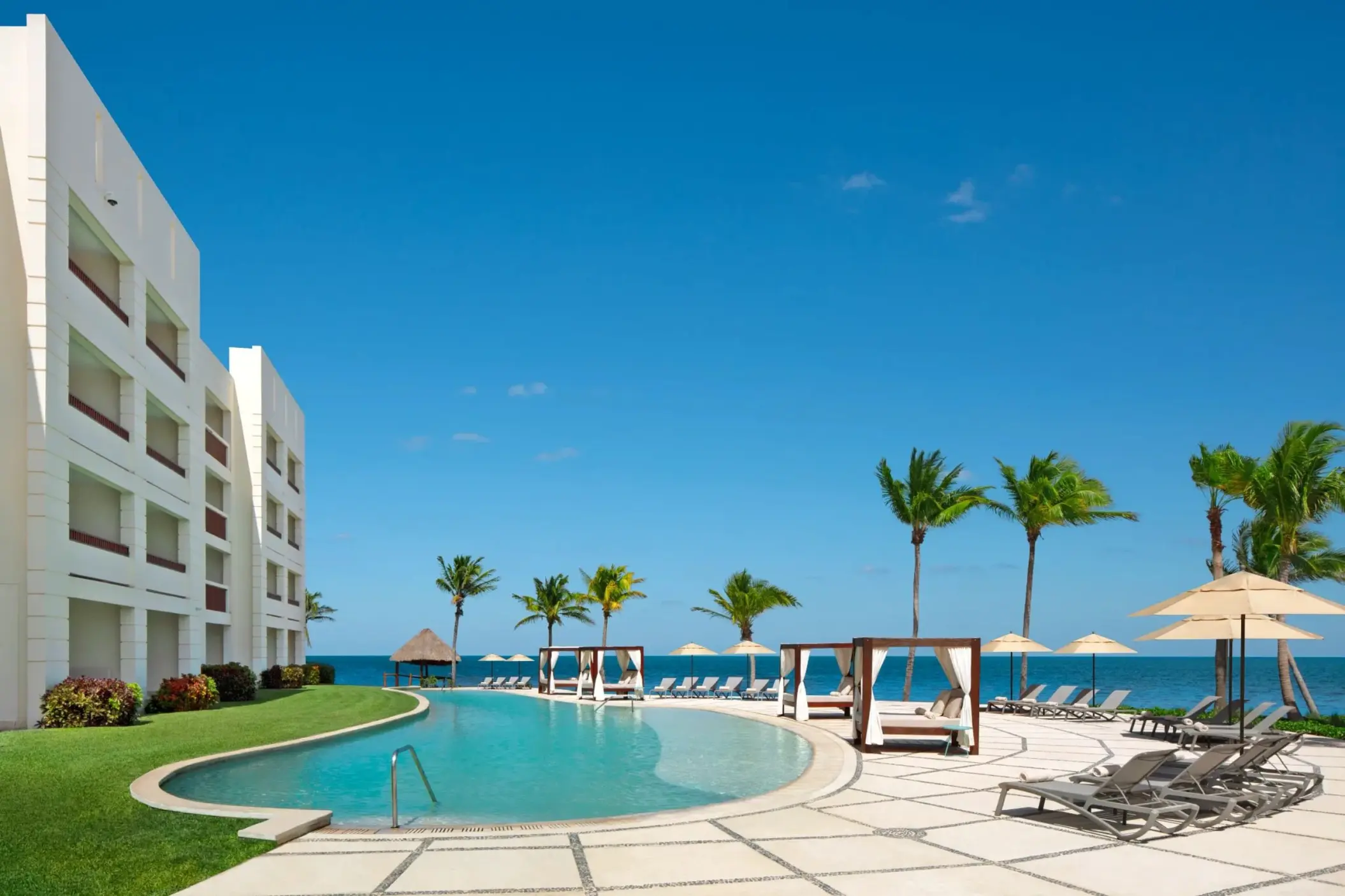 Oceanfront pool with cabanas and loungers at Dreams Puerto Morelos, Riviera Maya