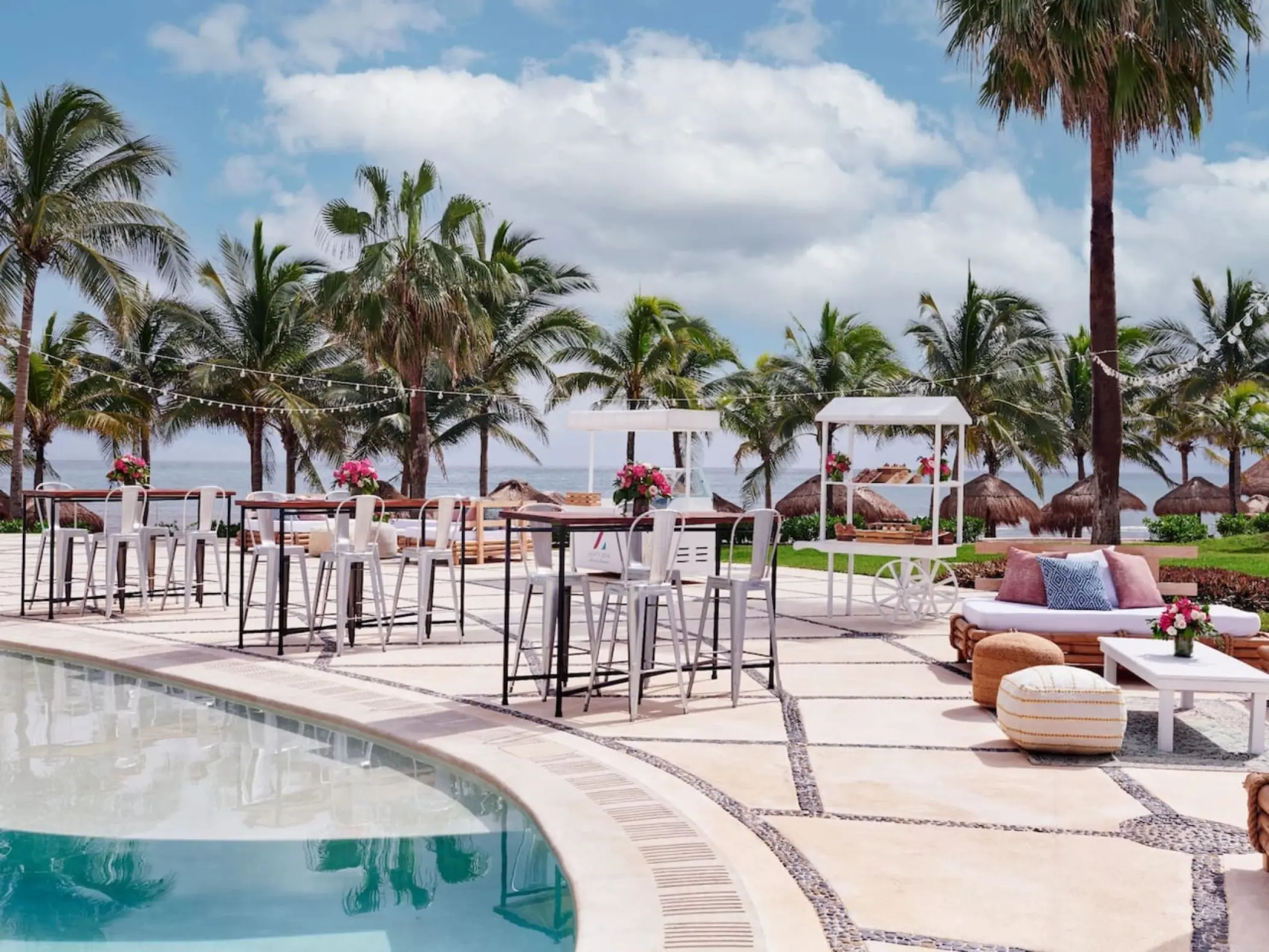 Pool deck wedding reception with high-top tables and lounge seating at Dreams Puerto Morelos, Riviera Maya