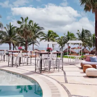 Pool deck wedding reception with high-top tables and lounge seating at Dreams Puerto Morelos, Riviera Maya